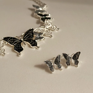 Detail of silver butterfly necklace and stud earrings set with black enamel oil drip