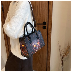 Detail of fashion skull tote bag with glowing orange eyes worn as a shoulder bag
