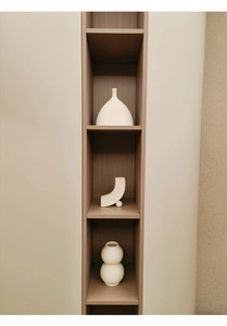 Dreiteiliges Set weißer minimalistischer Keramikvasen in einer Wandnische präsentiert