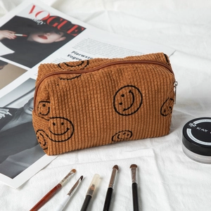 Brown corduroy cosmetic bag featuring a smiley face pattern on soft fabric