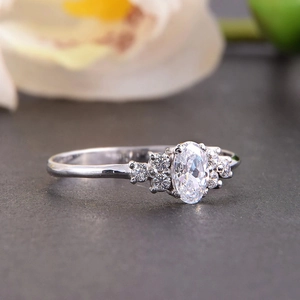 Detail van een ring met ovale edelsteen en zes zijdiamanten op een gestructureerd vlak