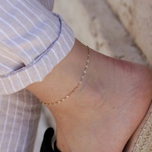 Close-up view of a delicate gold-plated stainless steel lip chain anklet on the ankle.