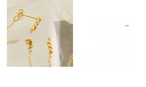 Detail view of gold geometric twist bar and fine tassel chain earrings on vintage card