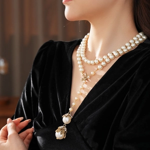 Detail of vintage pearl necklace with gold butterfly accents and large pendant on a model