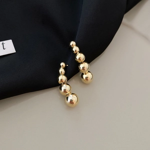 Detail of gold bead drop earrings with gradient size spheres and mirror polished finish
