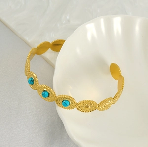 Détail d'un bracelet doré 18 carats avec pierres turquoise sur un coquillage blanc