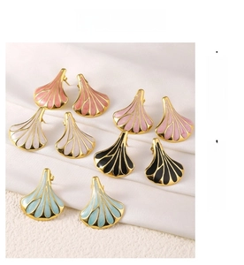 Detail of fan-shaped 18k gold plated earrings with colorful enamel inlays on silk