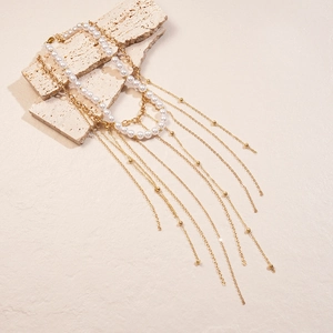 Close-up of a two-piece gold chain necklace with white imitation pearls and long tassels