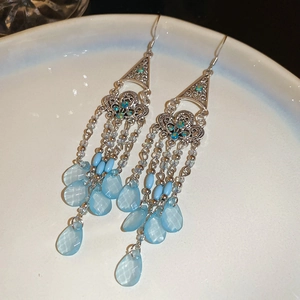 Detail of bohemian silver flower earrings with light blue crystal beads and tassels