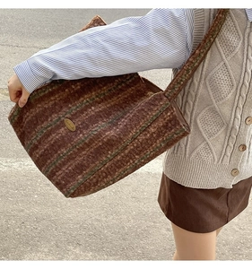 Detailed macro view of a brown striped wool tote bag with a golden metal logo detail