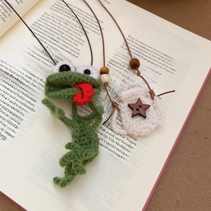 Detail of handmade crochet green frog pendant and knit star bag with wooden beads