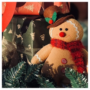 Detailed view of plush gingerbread man with scarf and hat amidst festive gift boxes
