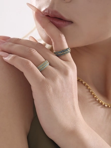 Dettaglio di un anello dorato a quattro file con zirconi blu e collana di perline abbinata