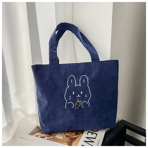 Detail of navy blue corduroy tote bag featuring an embroidered bunny holding a carrot