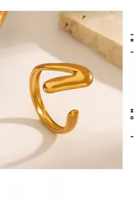 Detail of 18K gold-plated V-shaped open ring on a textured natural stone surface