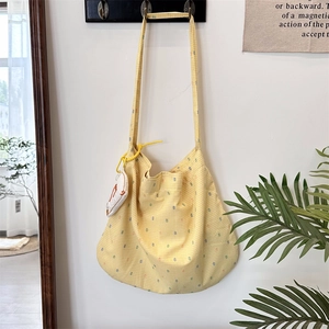 Close-up of yellow checkered canvas tote bag featuring a cute white duck plush charm