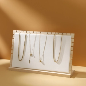 Detailed display of four gold pendant necklaces on a wooden jewelry showcase stand