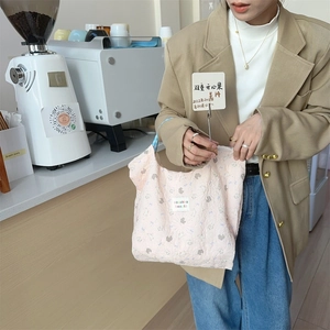 Detailed close-up of pink quilted tote bag with floral texture and brand label