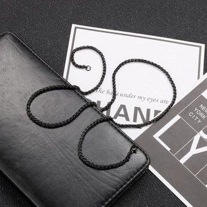 Macro detail of glossy black wheat chain necklace displayed on premium leather texture