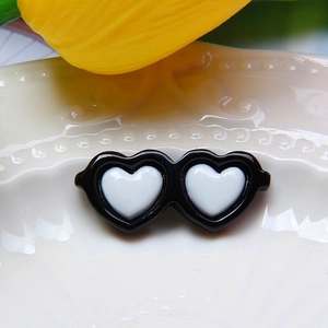 Detailed view of dual heart resin doll accessories with black frame on a seashell tray