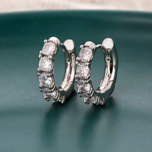 Dettaglio di orecchini a cerchio in argento con zirconi cubici su un piatto decorativo
