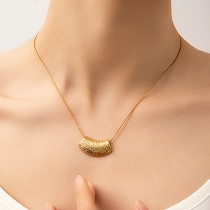 Golden titanium necklace with hammered texture pendant shown on a model neck