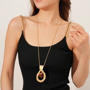 Detail of long gold necklace with drop-shaped wooden pendant on a model with elegant style