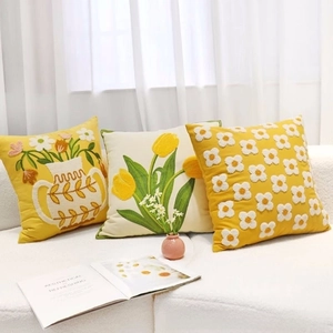 Close-up of tufted yellow tulips and floral embroidery on a premium sofa cushion cover