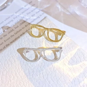 Close-up of vintage mini glasses brooches in gold and silver metal on retro background