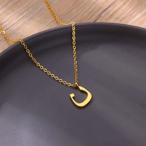 Macro view of minimalist gold plated stainless steel Arabic letter pendant necklace