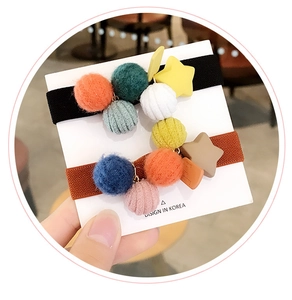 Dettaglio di due elastici in peluche con pompon colorati e ciondoli a stella gialla