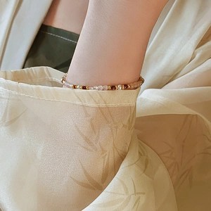 Detail of 18K gold plated beaded bracelet with pearls and stones on a silk sleeve