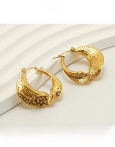 Detail of 18k gold plated stainless steel C-hoop earrings with a hammered metal texture