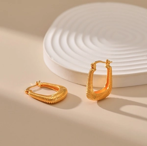 Detailed close-up of U-shaped gold earrings featuring unique spiral textured metal surfaces