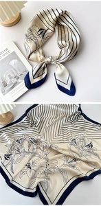 Detail view of navy blue and cream silk scarf with floral patterns and striped accents