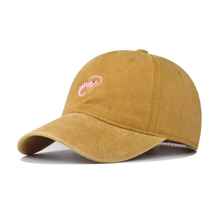 Detailed view of pink shrimp embroidery on a mustard washed cotton baseball cap