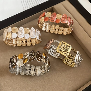 Detail of vintage square enamel stretch bracelets with colorful spiral patterns in a jewelry tray