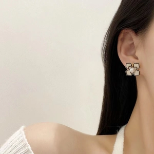 Elegant camellia flower stud earrings with white petals, black trim, and central pearl detail