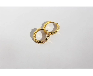 Macro shot of gold-plated bamboo-shaped hoop earrings with clear cubic zirconia stones
