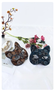 Close-up of elegant cat face masks with glitter patterns on smooth white fabric background