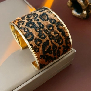 Detailed view of leopard print flocked wide cuff bracelet on a luxury display stand