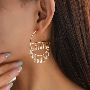 Close-up of model wearing gold geometric tassel earrings with dangling crystal rows