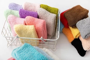 Detail showing various colors of thick winter coral fleece socks in a white wire basket
