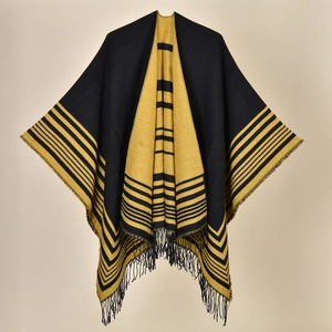Detailed close-up of the black and yellow striped knit cape featuring elegant fringe tassels