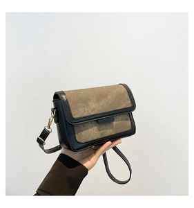 Detail of khaki and black shoulder bag with matte leather finish and golden metal buckle