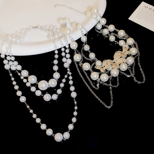 Detail of double-layer pearl necklaces featuring silver butterflies on a black background