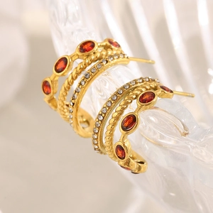 Detail of 18K gold plated C-shaped earrings with red zircon and clear crystals