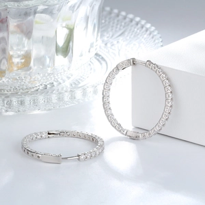 Close-up of silver-tone hoop earrings with full pavé cubic zirconia and hollowed patterns