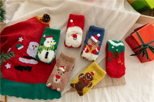 Detail of six festive coral fleece Christmas socks featuring cartoon holiday patterns
