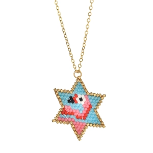Detail of handmade beaded star pendant necklace with abstract face design and gold chain